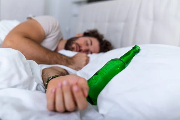 飲んだ後だ 酔った髭を生やした大人の男は ベッドの上に横になり アルコールをたくさん飲んだ後 ベッドの上に空のボトル アルコール依存症 アルコール中毒や人々の概念 — ストック写真
