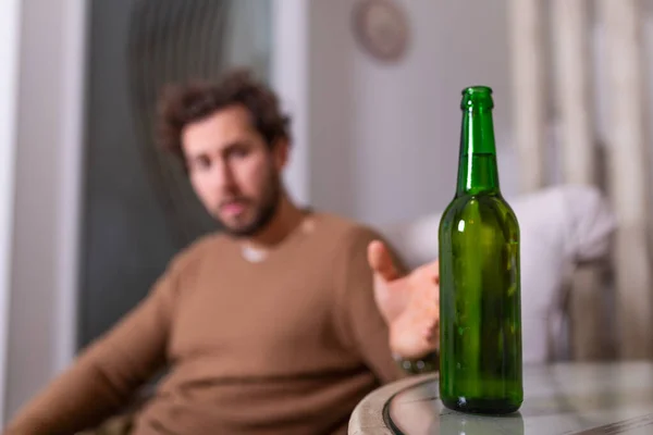 酗酒的男人伸手去拿一瓶啤酒 男人一个人在家喝酒 酗酒和人们的观念 男性酗酒者单独在家喝啤酒 — 图库照片