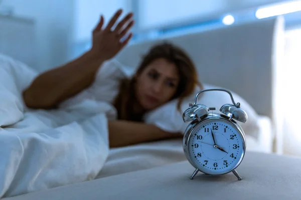 Woman lying in bed suffering from insomnia, Sleepless and desperate beautiful caucasian woman awake at night not able to sleep, feeling frustrated and worried suffering from insomnia in sleep disorder