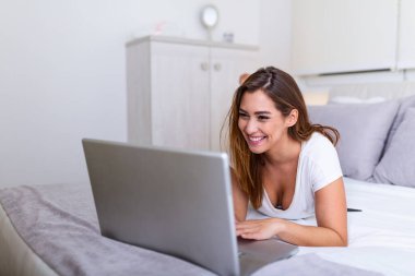 Güzel, genç bir üniversite öğrencisi evde yatağında ödev yapıyor. Genç ve güzel bir kadın laptopuyla yatak odasında sınav hazırlıyor. Ev kavramından bağımsız çalışma