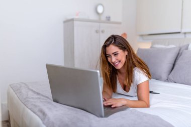 Güzel, genç bir üniversite öğrencisi evde yatağında ödev yapıyor. Genç ve güzel bir kadın laptopuyla yatak odasında sınav hazırlıyor. Ev kavramından bağımsız çalışma