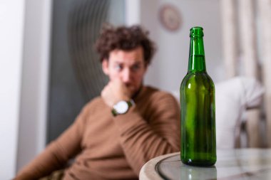 Depresyonda olan, kendini kötü hisseden, evde yalnız başına bira içen, alkol bağımlısı, alkolik, alkolik, alkolik, bunalımlı genç bir adam.