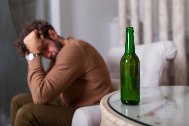 Alkol şişesinin arkasında içki içen isimsiz alkoliğin silueti. Alkol alışkanlıklarıyla kavga eden bir adam, evde kanepede oturup içki içen bir adam.