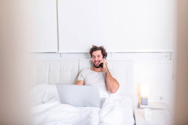 Odaklanmış genç girişimcinin fotoğrafı hafta sonları çalışır patronunun evde yatmasını istediğini rapor etmek için bilgisayarını kullanır. Evden çalışan adam.