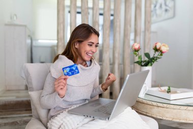 Genç bir kadın banka kartıyla internetten alışveriş yapıyor. Güzel kız evde online alışveriş için dizüstü bilgisayar kullanıyor. Güzel kız evde online alışveriş için dizüstü bilgisayar kullanıyor.