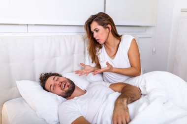Couple in bed, man snoring and woman can't sleep. Snoring man and young woman. Couple sleeping in bed. Young girl can't sleep because of her man's snoring holding his nose. Snoring man problem clipart