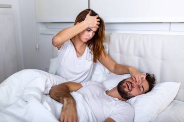 Couple in bed, man snoring and woman can't sleep. Snoring man and young woman. Couple sleeping in bed. Young girl can't sleep because of her man's snoring holding his nose. Snoring man problem clipart
