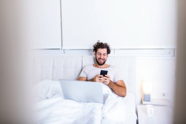 Odaklanmış genç girişimcinin fotoğrafı hafta sonları çalışır patronunun evde yatmasını istediğini rapor etmek için bilgisayarını kullanır. Evden çalışan adam.