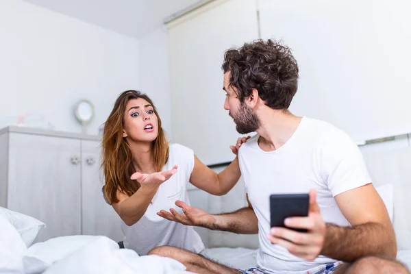 I can't stand when he's working all the time. Young unhappy woman and her boyfriend who uses the phone in bed. Family conflict with wife husband in bed