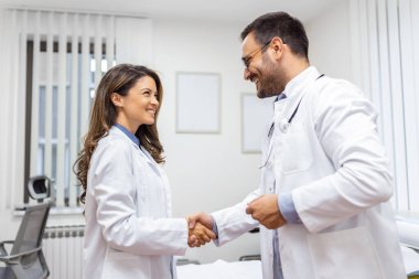 Klinikte dururken el sıkışan iki profesyonel kendine güvenen doktor. Kafkas tıbbi toplantısının takım çalışması ve hastanede el sıkışma. Tıbbi ekip, sağlık konsepti.