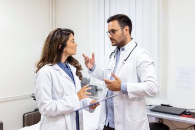 Beyaz önlüklü iki doktor ellerinde dosya tutuyorlar. Çok başarılılar, gülümseyin ve birlikte çalışın.