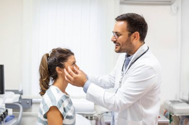 Yetişkin bir kadın göz doktorunun muayenehanesini ziyaret ediyor. Klinikteki genç bayanın gözlerini muayene eden doktor..