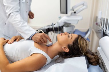 Doktor klinikteki kadın hastaya ultrason yapıyor. Otoimmün tiroidit teşhisi ve tedavisi
