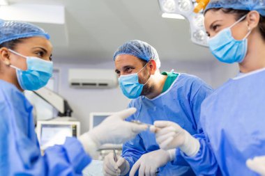 Doktor ve hemşire tıbbi ekibi hastanedeki acil serviste ameliyat yapıyor. Asistan ameliyat sırasında cerrahlara makas ve aletler dağıtıyor.