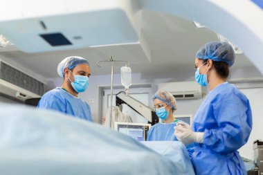 Ameliyathanede cerrahi maskeli cerrahlar 3 boyutlu görüntü güdümlü ameliyat makinesi kullanıyorlar.