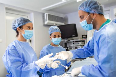 Group of surgeons wearing safety masks performing operation. Medicine concept. surgery, medicine and people concept - group of surgeons at operation in operating room at hospital
