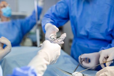 Doktor ve hemşire tıbbi ekibi hastanedeki acil serviste ameliyat yapıyor. Asistan ameliyat sırasında cerrahlara makas ve aletler dağıtıyor.