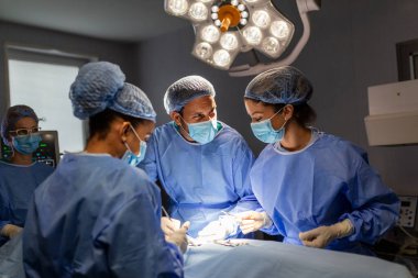 Muhtelif profesyonel cerrah ekipleri, asistanlar ve hemşireler bir hastayı ameliyat odasında ameliyat ediyorlar. Cerrahlar konuşur ve aletleri kullanır. Gerçek Modern Hastane.