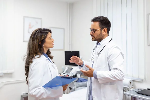 Team of doctors working together on patients file at hospital. Medical staff analyzing report and working at clinic. Woman doctor having discussion in a hospital with colleague