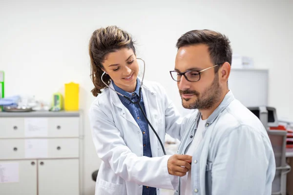 Den Unge Läkaren Använder Ett Stetoskop Och Lyssnar Patientens Hjärtslag — Stockfoto