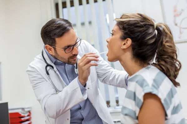 医師検査へらを使用して患者の喉を調べる 耳鼻咽喉科医が女の喉検査を行う 患者は喉の検査まで口を開けて — ストック写真
