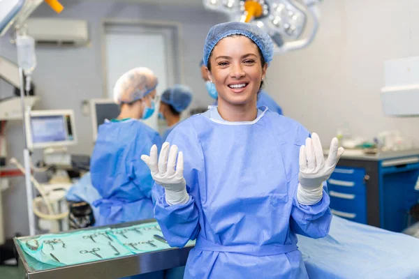 Portrait of young female surgeon doctor surrounded by her team. Group of surgeon in operation theatre.