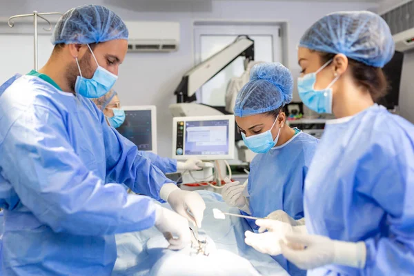 Group of surgeons wearing safety masks performing operation. Medicine concept. surgery, medicine and people concept - group of surgeons at operation in operating room at hospital