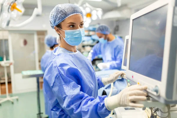 病院で手術前に患者を鎮静させながら 保護ギアチェックモニターを装着した手術室で働く麻酔医 — ストック写真