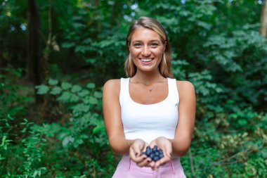 Bir avuç taze toplanmış organik yaban mersinli kadın.