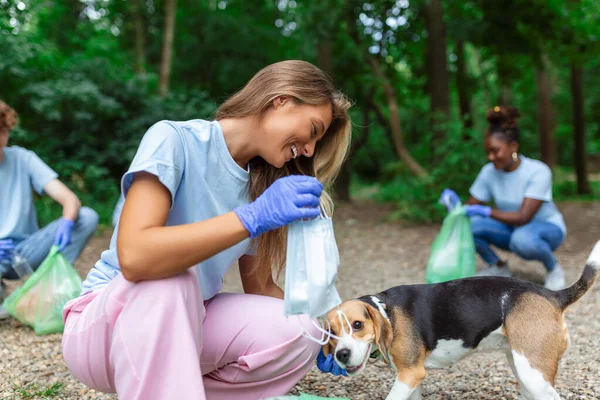 Young woman with her dog waste collector busy separating medical or PPE waste from plastic garbage during the covid-19 coronavirus pandemic