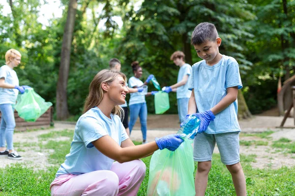 Mother and kids are picking up the garbage to clean up the forest