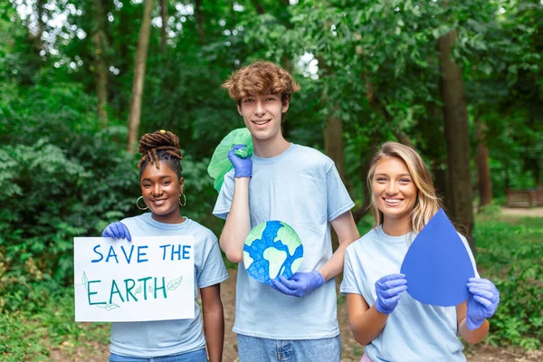 Diverse Group of People Picking Up Trash in The Park Volunteer Community Service. Happy international volunteers holding placard with \'Save the Earth\' message.