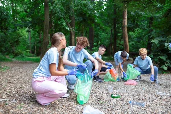 Young responsible people doing community charity work in the park. Group of people, cleaning together in public park, saving the environment.