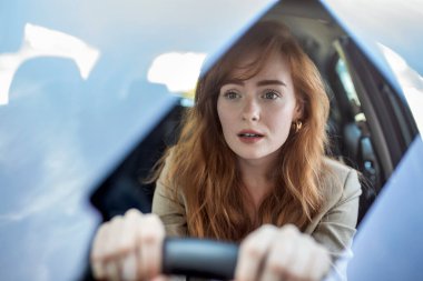 Dehşete düşmüş genç bir kadın araba kullanıyor ve araba kazası geçiriyor. Önündeki yolda korkmuş ve şaşırmış bir şekilde araba kullanan yetişkin bir kadın. Araba Kazasında Kadın