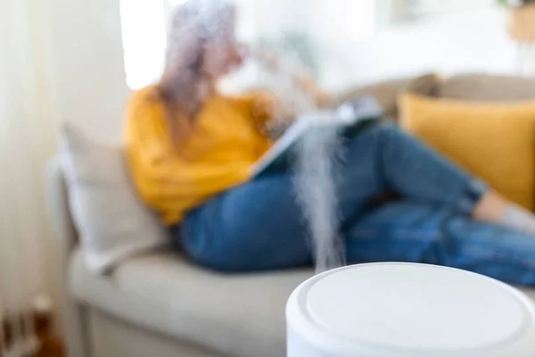 Air purifier in cozy white Living room for filter and cleaning removing dust PM2.5 HEPA at home with woman reading a book on sofa,for fresh air and healthy life,Air Pollution Concept