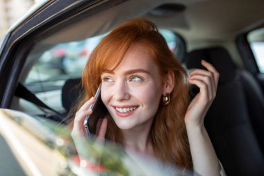 İş kadını araba kullanırken birden fazla iş yapıyor, telefonda konuşuyor. Araba kullanırken gülümseyen kadın telefonda konuşuyor. Araba sürerken cep telefonunda Konuşan Kadın