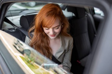 Güzel iş kadını lüks arabasının arka koltuğunda ofisten işe gidip geliyor. Girişimci Yolcu Şehir Caddesinde Taksiyle Seyahat Ediyor