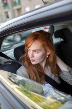 Arabanın camından dışarı bakan genç bir kadın. Arabanın arka koltuğunda pencereden dışarı bakan genç bir kadın..