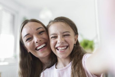 Küçük kız, genç anne web kamerasıyla karşı karşıya. Sevimli kız akıllı telefon kullanır ablanla selfie çekerken, video blokları kaydederken, eğlenceli aktivite konseptinin keyfini çıkarırken iyi eğlenceler.