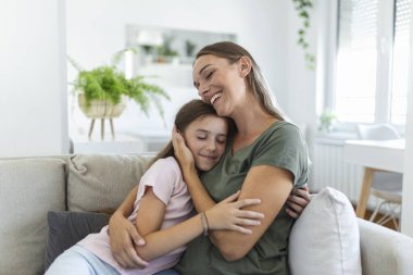 Tatlı güzel kızının genç annesine sarılıp yattığı yakın çekim. Sevgili anne, tatlı kızını evdeki kanepede kucaklıyor..