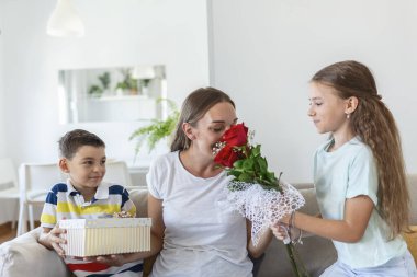 Bir buket gül çiçeğiyle neşeli küçük bir kız ve hediye kutusuyla gülümseyen ve anneler gününde annelerini tebrik eden en küçük kardeşi. Anneler Günün kutlu olsun.!