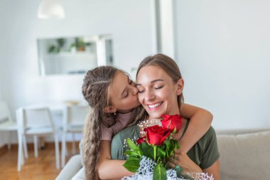 Seni seviyorum anne! Çekici genç bir kadın ve küçük tatlı bir kız birlikte evde vakit geçiriyorlar, aşk sembolü ve çiçekli el yapımı kart için teşekkür ediyorlar. Mutlu aile kavramı. Anneler Günü..