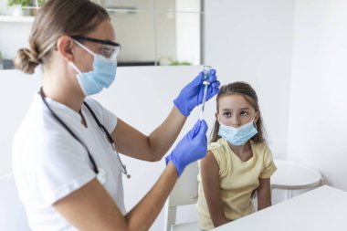 Virüse karşı bağışıklık kampanyası konsepti. Doktor aşılayan kız. Tıbbi maskeli kız covid-19 aşısı oluyor, doktor hastanede koronavirüs aşısı yapıyor..