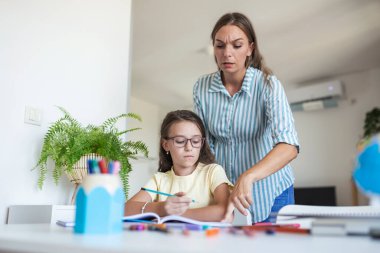 Stresli anne-kız ödevleri ve okul sorunları konsepti yüzünden hayal kırıklığına uğradı. Zavallı küçük kız annesine sırtını döndü, sıkıcı ev ödevleri yapmak istemiyor.
