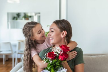Seni seviyorum anne! Çekici genç bir kadın ve küçük tatlı bir kız birlikte evde vakit geçiriyorlar, aşk sembolü ve çiçekli el yapımı kart için teşekkür ediyorlar. Mutlu aile kavramı. Anneler Günü..
