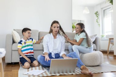 Küçük yaramaz çocukların gürültüsü ve dikkat dağıtan anne serbest çalışan laptopa konsantre olmaya çalışan ve aydınlık oturma odasındaki masada çalışan kafaları sıkan