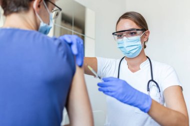 Pratisyen hekimin klinikteki eski hastaya fotokopi alanı aşılaması. Doktor, hastanedeki yaşlı adama iğne yapıyor. Covid-19 ya da Coronavirus aşısı yapmadan önce elinde şırınga tutan hemşire..