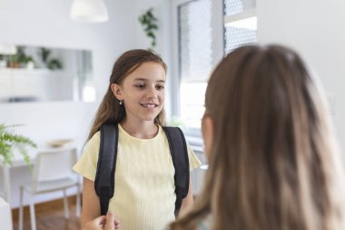 Küçük çocuğunun okula hazırlanmasına yardım eden genç bir anne, küçük kızını okula hazırlayan bir anne.