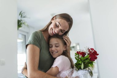 Seni seviyorum anne! Çekici genç bir kadın ve küçük tatlı bir kız birlikte evde vakit geçiriyorlar, aşk sembolü ve çiçekli el yapımı kart için teşekkür ediyorlar. Mutlu aile kavramı. Anneler Günü..
