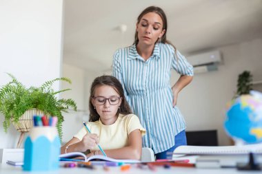 Çocuk ev ödevi yaparken konsantrasyon sorunu yaşıyor. Stresli Anne ve Kızı Başarısızlık Ödevleri ve Okul Sorunları İçin Hayal kırıklığına uğradı. Anne, kızına zor ödevlerinde yardım et.